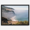 A fine art print of a misty beach in Big Sur, California. Waves crash against the shore as fog drapes over the rugged coastal cliffs, creating a serene, atmospheric scene
