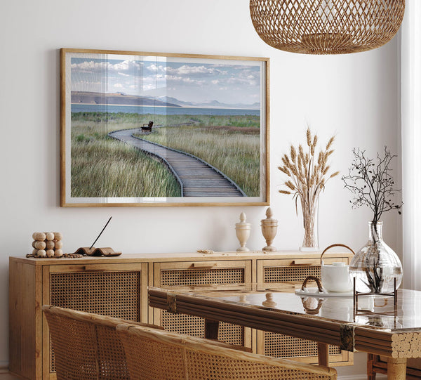 Framed Mono Lake nature photography print featuring a winding boardwalk through tall grasses, leading to a quiet bench beside the lake with mountains in the background.