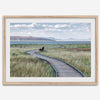 Framed Mono Lake nature photography print featuring a winding boardwalk through tall grasses, leading to a quiet bench beside the lake with mountains in the background.