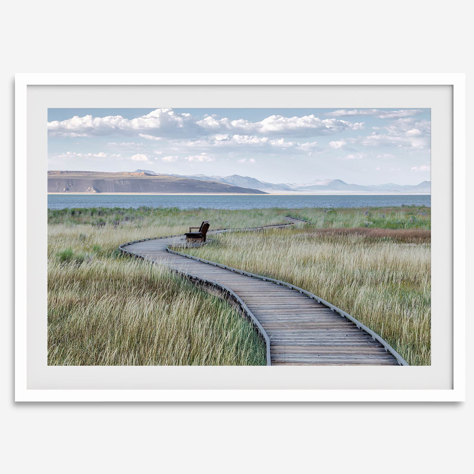 Framed Mono Lake nature photography print featuring a winding boardwalk through tall grasses, leading to a quiet bench beside the lake with mountains in the background.