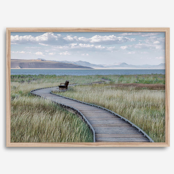 Framed Mono Lake nature photography print featuring a winding boardwalk through tall grasses, leading to a quiet bench beside the lake with mountains in the background.