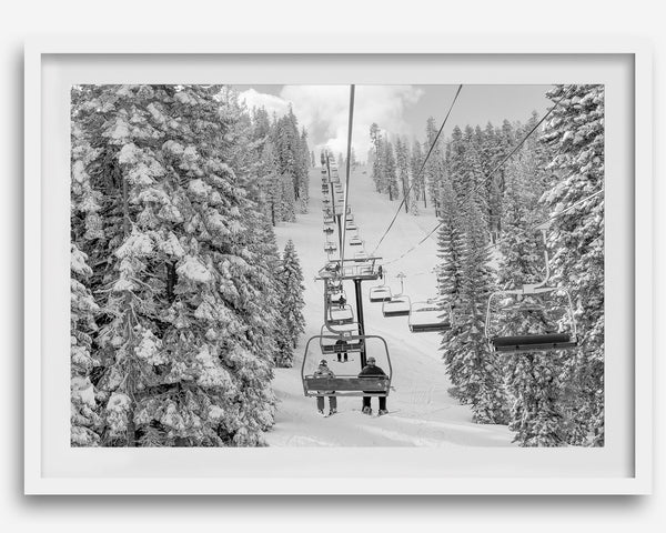 A fine art black and white mountain ski print showing a ski lift winding up the mountain with a stunning winter snow forest around it.