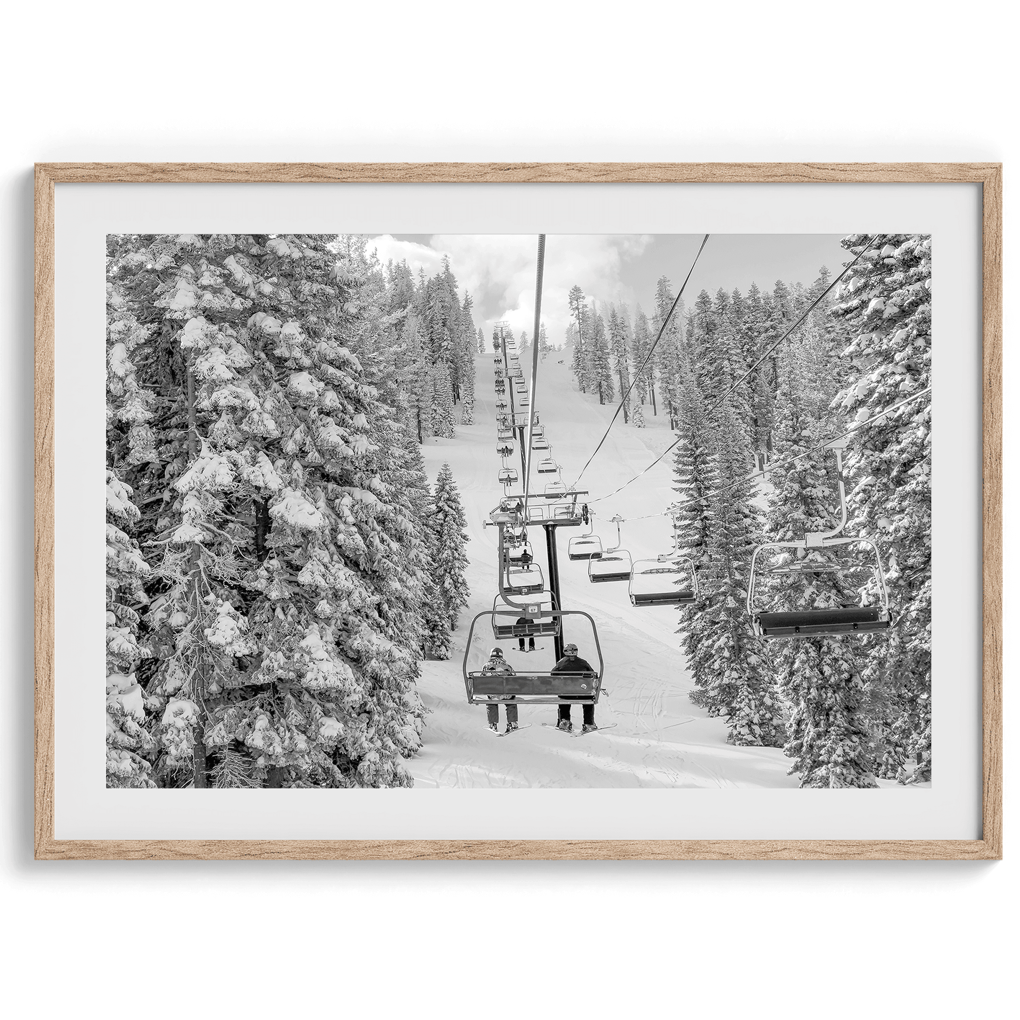 A fine art black and white mountain ski print showing a ski lift winding up the mountain with a stunning winter snow forest around it.