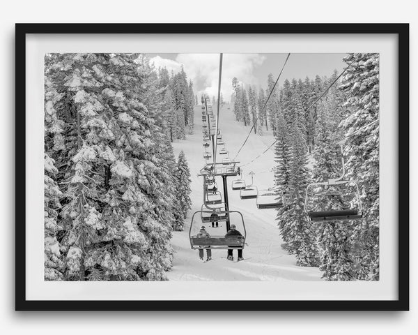A fine art black and white mountain ski print showing a ski lift winding up the mountain with a stunning winter snow forest around it.