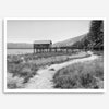 A fine art black and white vintage style framed photography print featuring a rustic old boathouse nested on a Lake Tahoe beach.