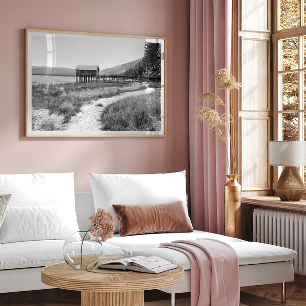 A fine art black and white vintage style framed photography print featuring a rustic old boathouse nested on a Lake Tahoe beach.