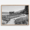 A fine art black and white vintage style framed photography print featuring a rustic old boathouse nested on a Lake Tahoe beach.