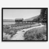 A fine art black and white vintage style framed photography print featuring a rustic old boathouse nested on a Lake Tahoe beach.