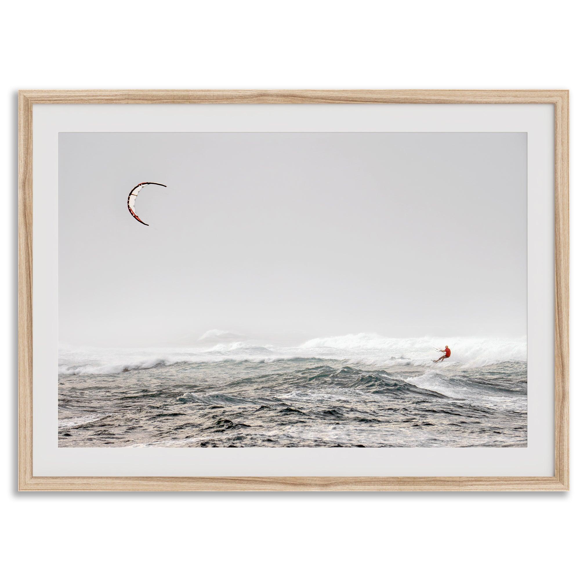 Wind surfer riding waves in Maui with kite above and misty ocean below.