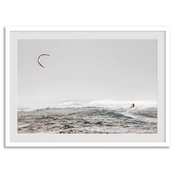 Wind surfer riding waves in Maui with kite above and misty ocean below.