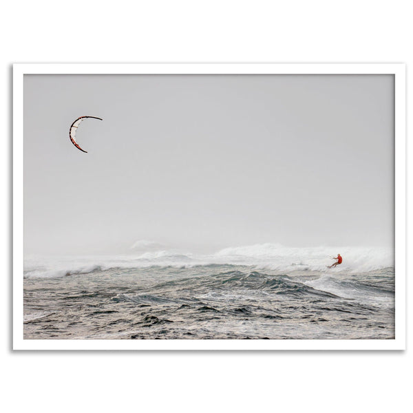 Wind surfer riding waves in Maui with kite above and misty ocean below.