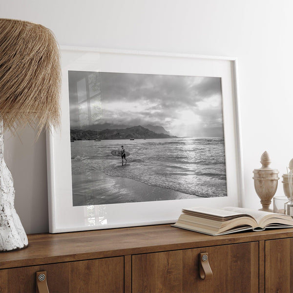 Surfer Wall Art featuring a lone surfer emerging from the ocean at Hanalei Bay in black-and-white photography.