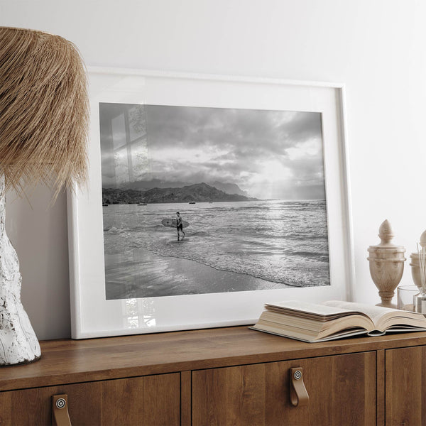 Surfer Wall Art featuring a lone surfer emerging from the ocean at Hanalei Bay in black-and-white photography.