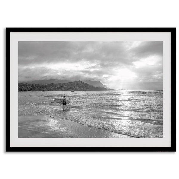 Surfer Wall Art featuring a lone surfer emerging from the ocean at Hanalei Bay in black-and-white photography.