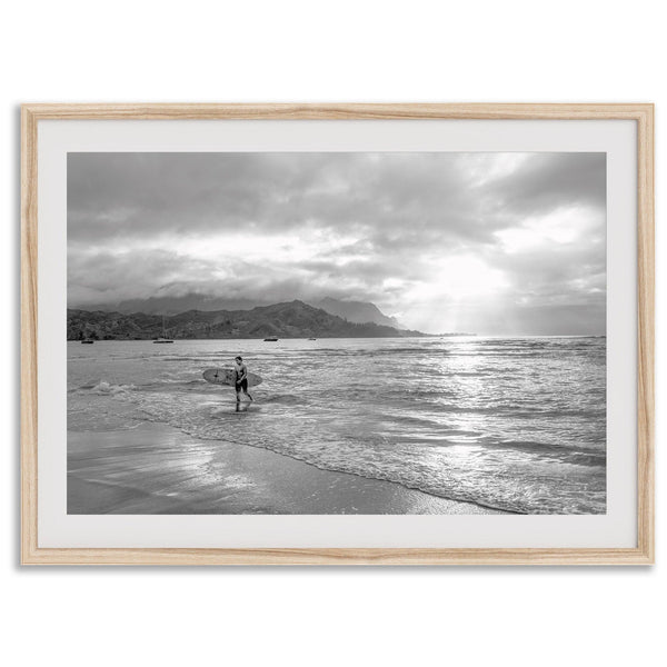 Surfer Wall Art featuring a lone surfer emerging from the ocean at Hanalei Bay in black-and-white photography.