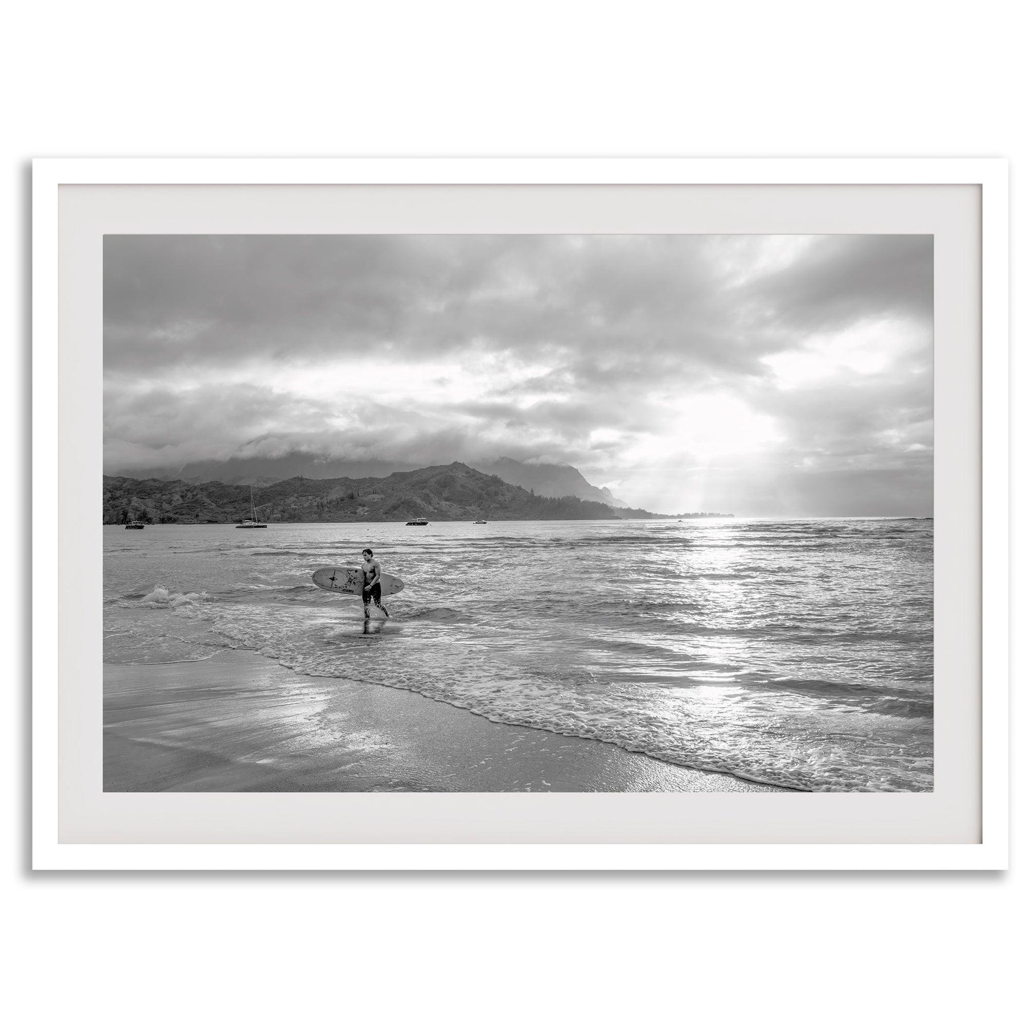 Surfer Wall Art featuring a lone surfer emerging from the ocean at Hanalei Bay in black-and-white photography.