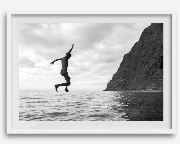 Black and white fine art print of a man mid-jump into the ocean near the cliffs of Na Pali Coast, Kauai.