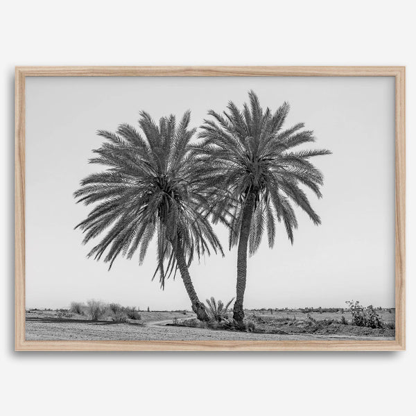 Black and white fine art print of two palm trees in a minimalist desert landscape with clear sky.