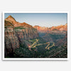 Framed Zion National Park print with winding road illuminated through red cliffs and majestic canyon scenery at dusk.