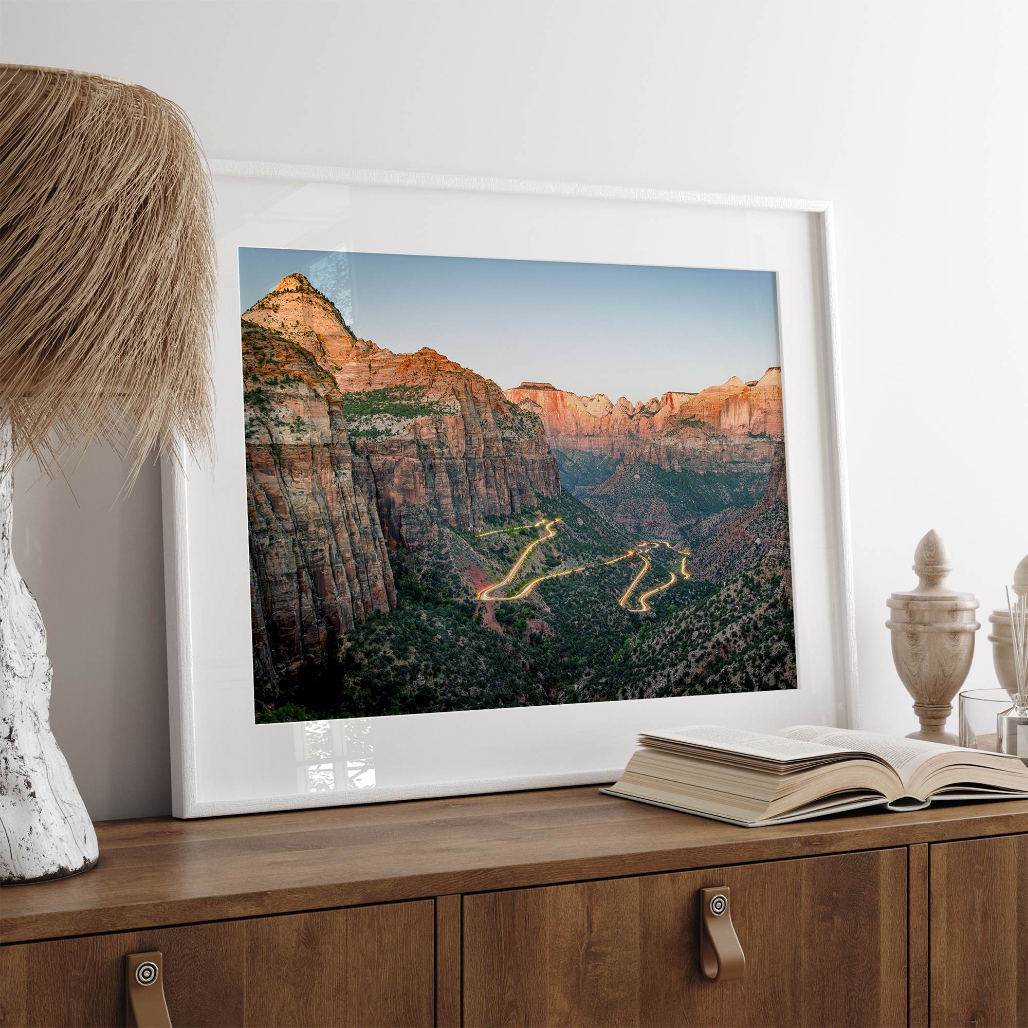 Framed Zion National Park print with winding road illuminated through red cliffs and majestic canyon scenery at dusk.