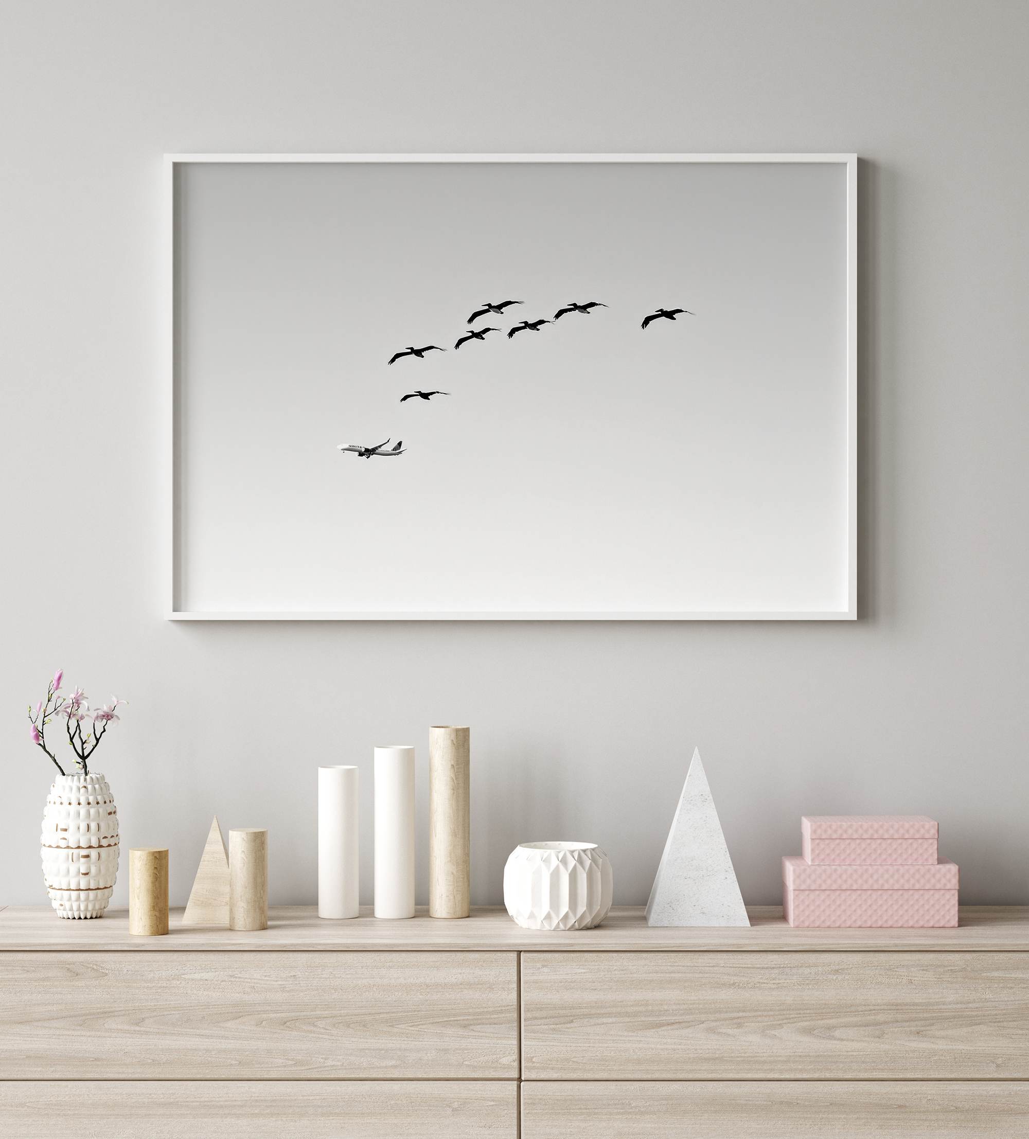 birds in flight wall art with airplane, framed black and white minimalist photography print on white wall.