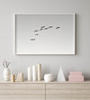 birds in flight wall art with airplane, framed black and white minimalist photography print on white wall.
