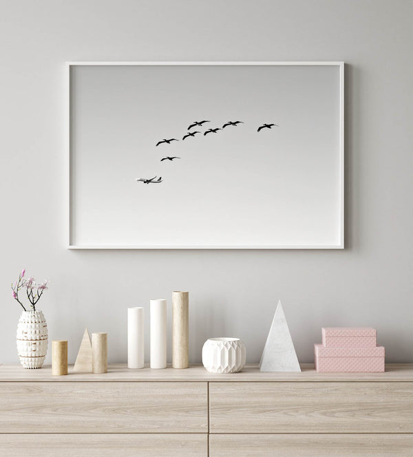 birds in flight wall art with airplane, framed black and white minimalist photography print on white wall.
