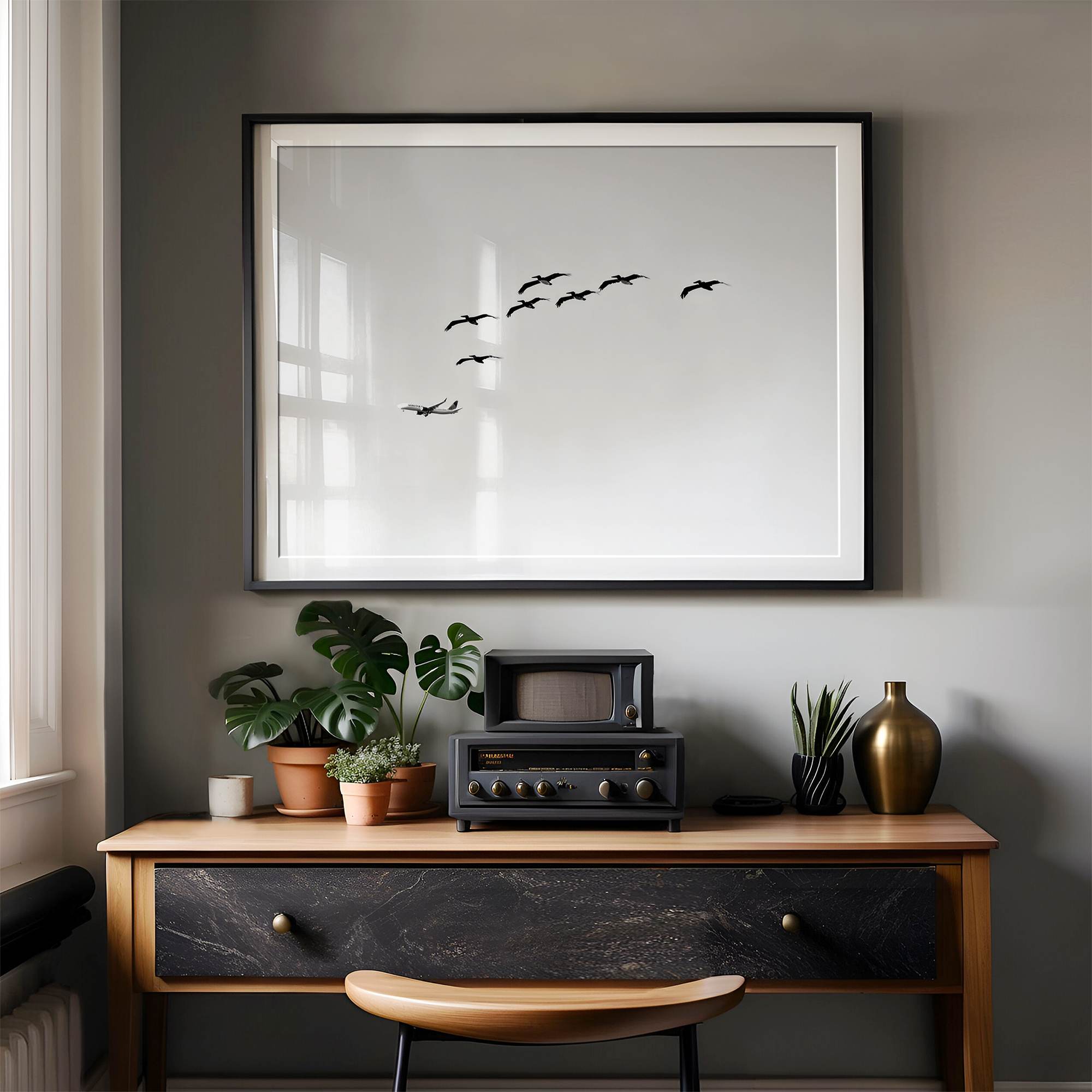 birds in flight wall art with airplane, framed black and white minimalist photography print on white wall.