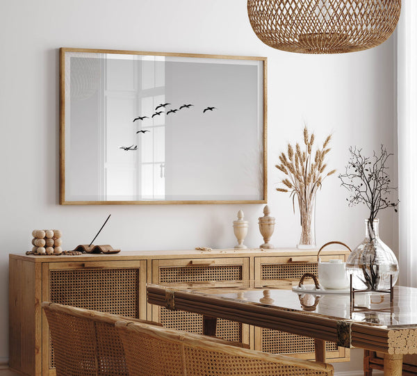birds in flight wall art with airplane, framed black and white minimalist photography print on white wall.