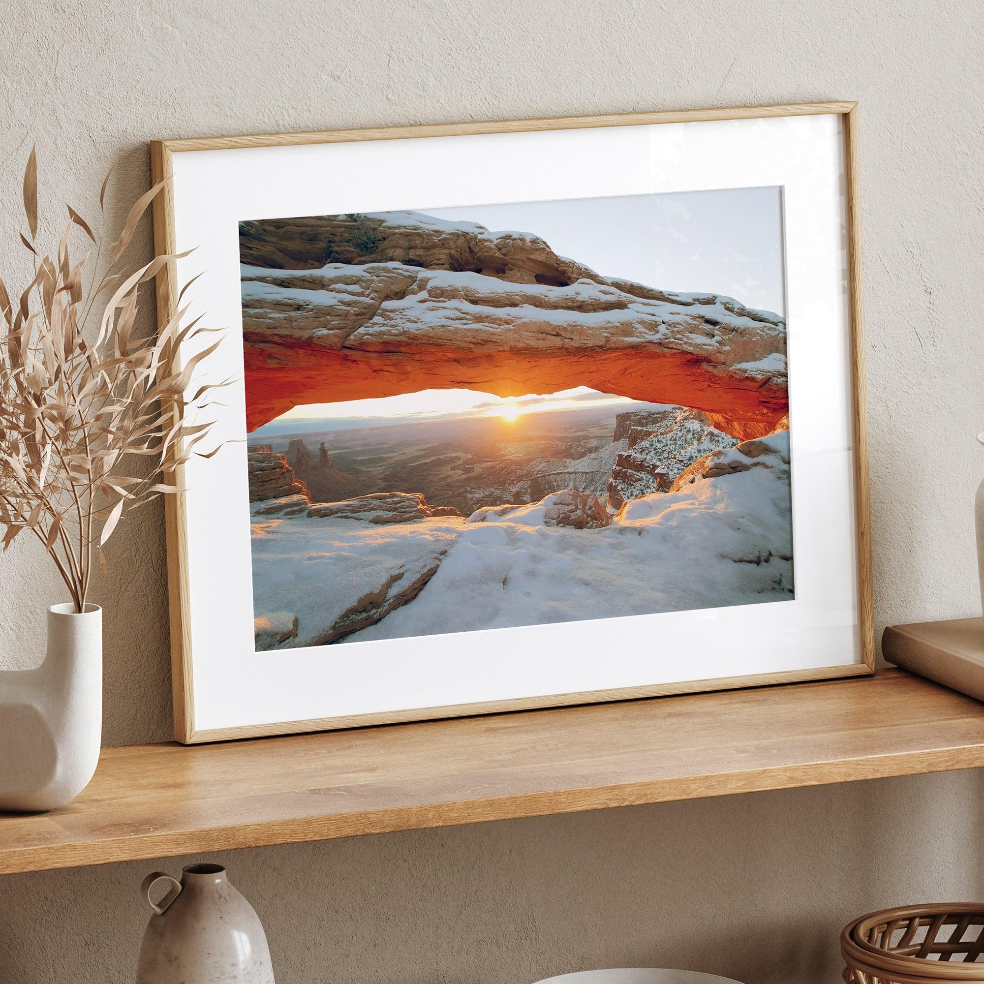 Canyonlands wall art featuring Mesa Arch at sunrise, with sunlight shining through the snow-covered arch over a vast canyon landscape.