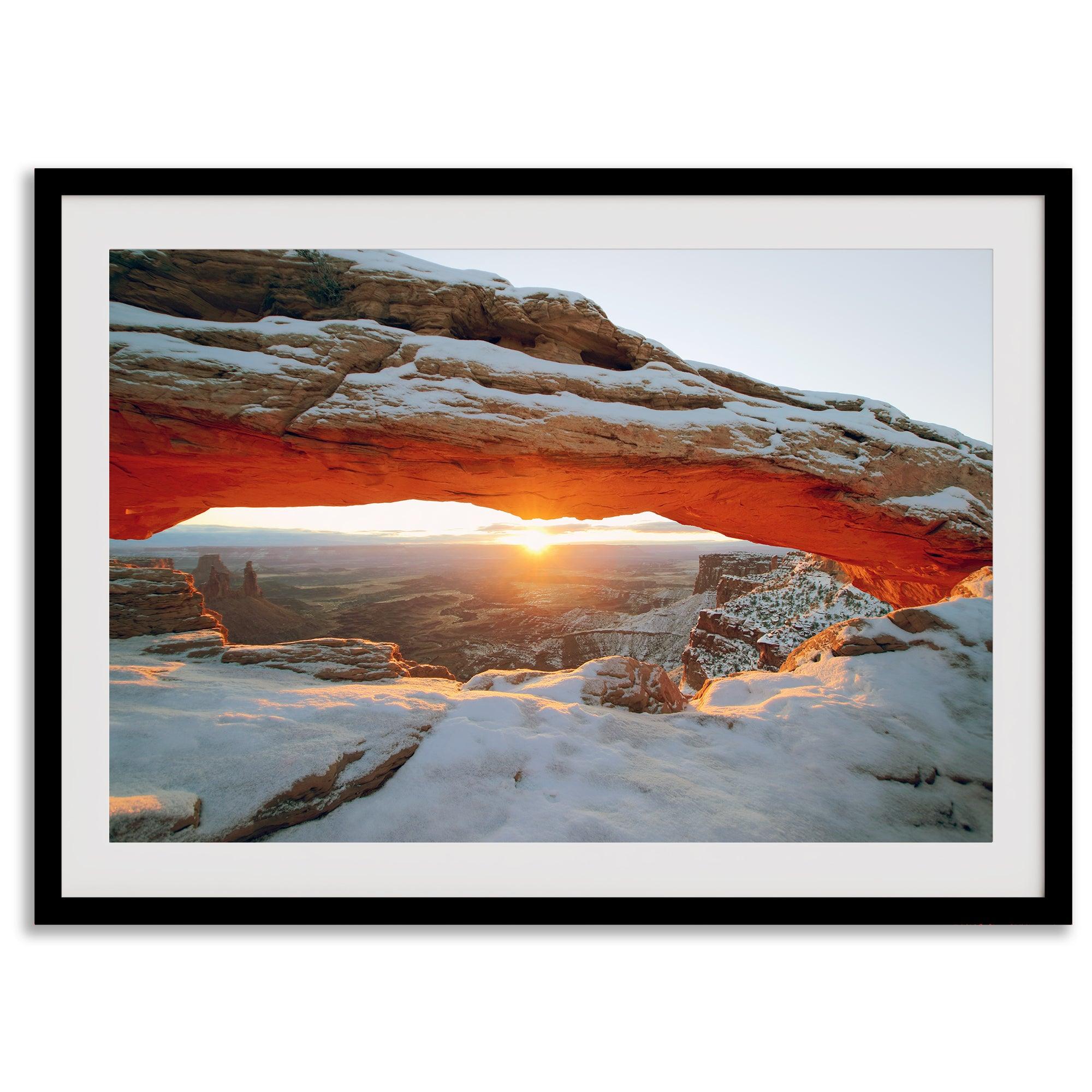 Canyonlands wall art featuring Mesa Arch at sunrise, with sunlight shining through the snow-covered arch over a vast canyon landscape.