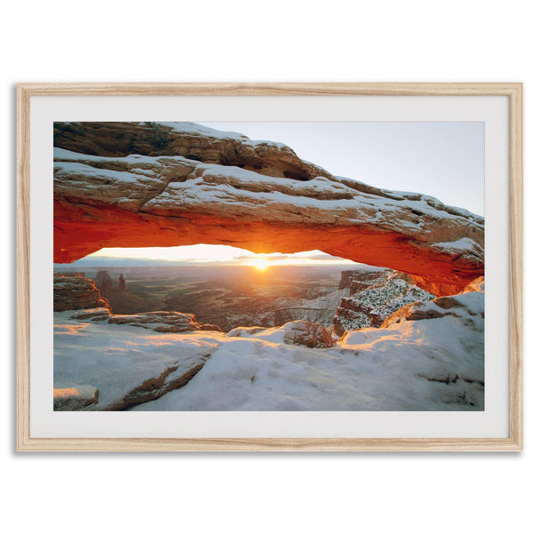 Canyonlands wall art featuring Mesa Arch at sunrise, with sunlight shining through the snow-covered arch over a vast canyon landscape.