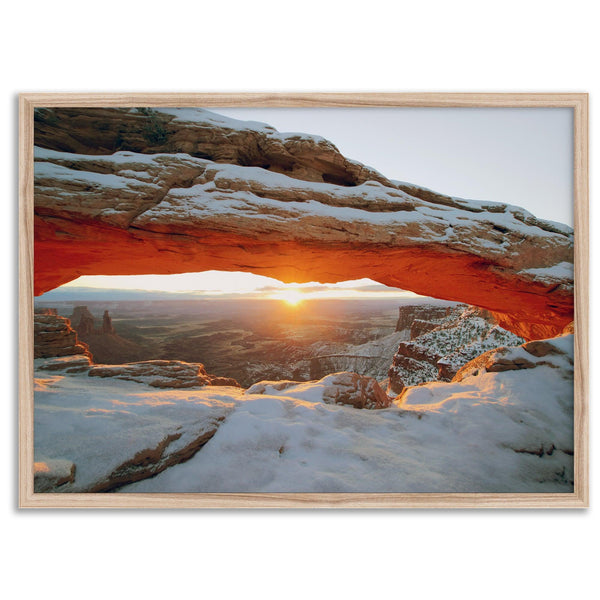 Canyonlands wall art featuring Mesa Arch at sunrise, with sunlight shining through the snow-covered arch over a vast canyon landscape.