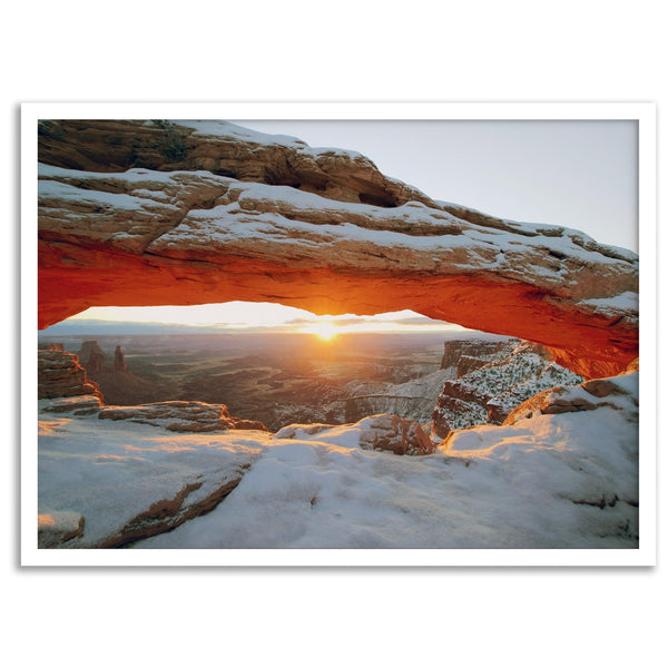 Canyonlands wall art featuring Mesa Arch at sunrise, with sunlight shining through the snow-covered arch over a vast canyon landscape.