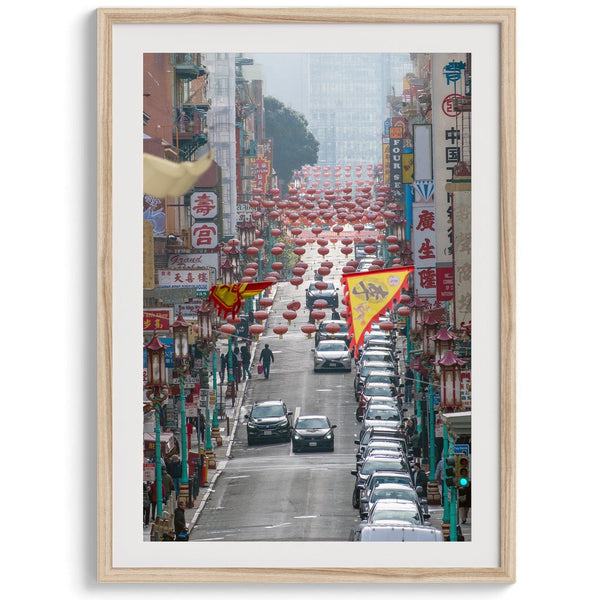 Red lanterns line Grant Avenue in San Francisco’s Chinatown, framed by colorful signs and bustling city life. Available as a framed or unframed print.