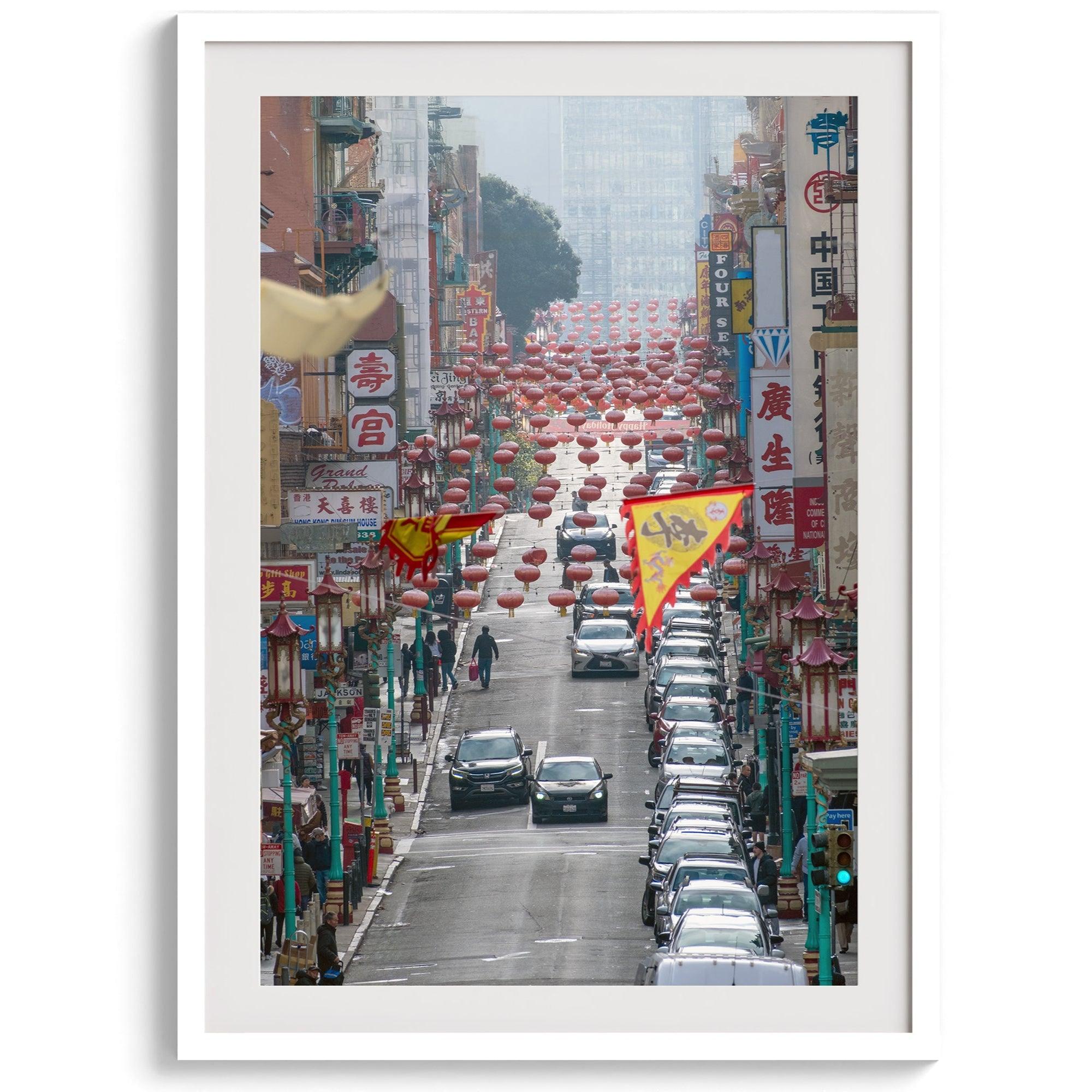 Red lanterns line Grant Avenue in San Francisco’s Chinatown, framed by colorful signs and bustling city life. Available as a framed or unframed print.