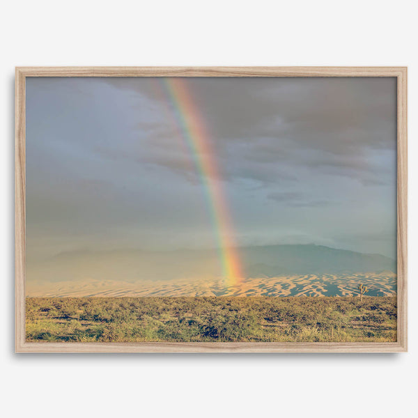 Desert landscape artwork of a rainbow over Arizona sand dunes with distant mountains.