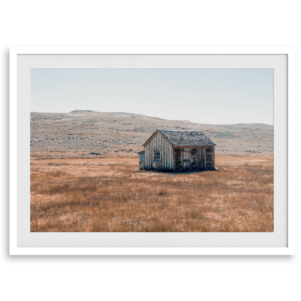 Rustic farmhouse in the Wild West surrounded by golden fields, capturing the essence of American frontier life.