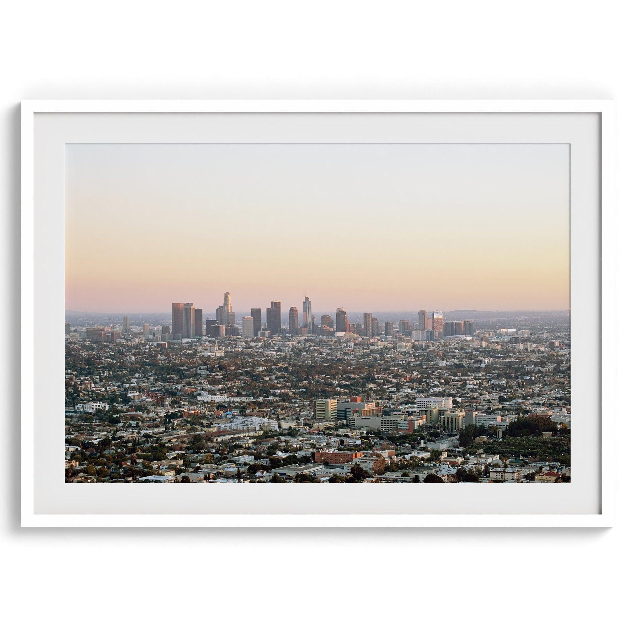 Los Angeles cityscape bathed in a vibrant sunset, showcasing the city's iconic buildings from above