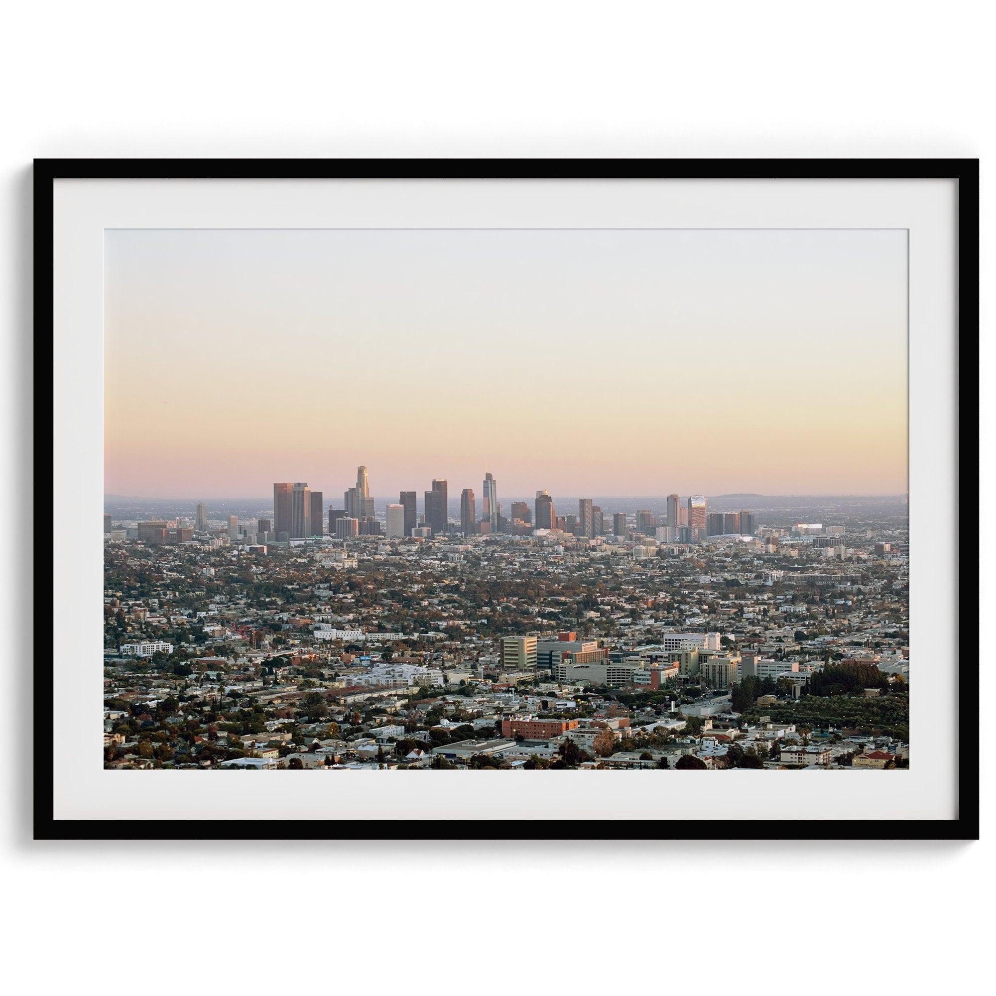 Los Angeles cityscape bathed in a vibrant sunset, showcasing the city's iconic buildings from above