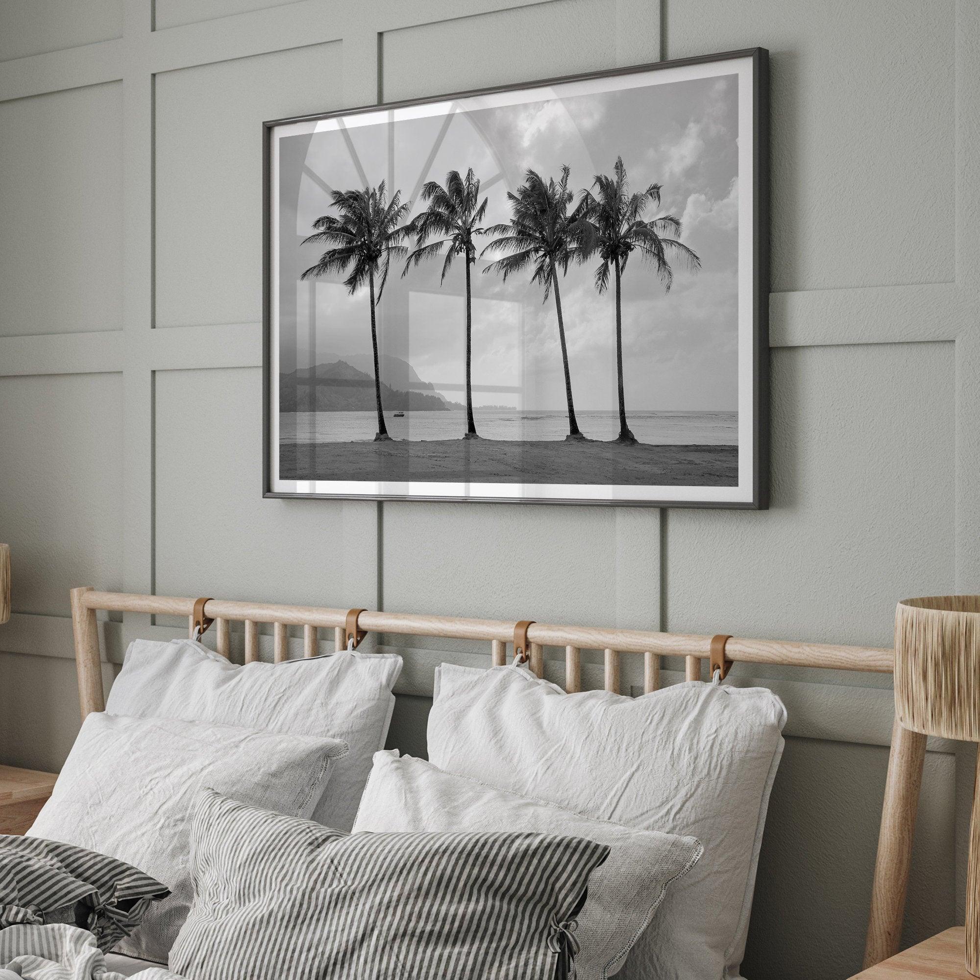 Black and white photo of Kauai beach with four palm trees, calm ocean waves, and shaded island mountains in the distance