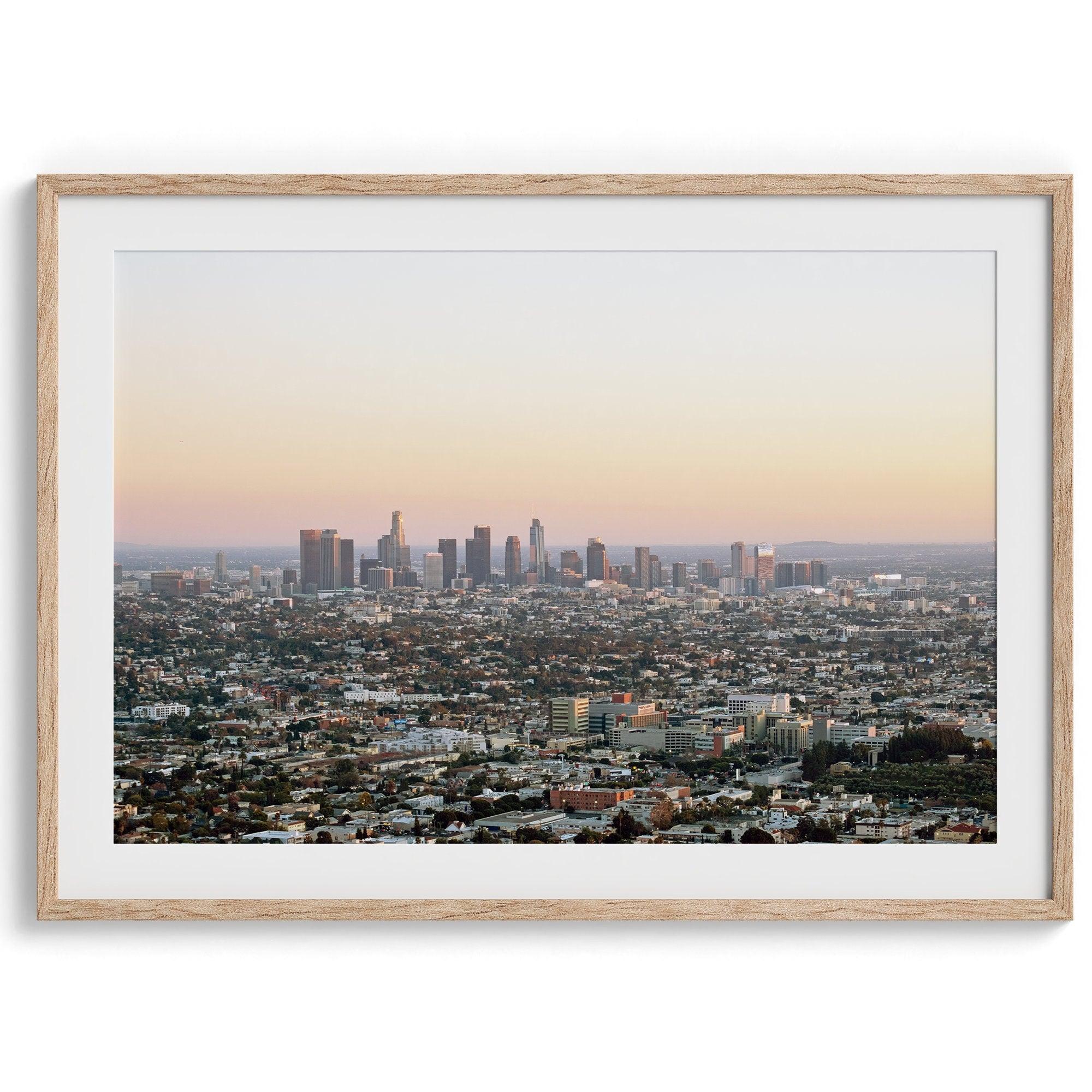 Los Angeles cityscape bathed in a vibrant sunset, showcasing the city's iconic buildings from above