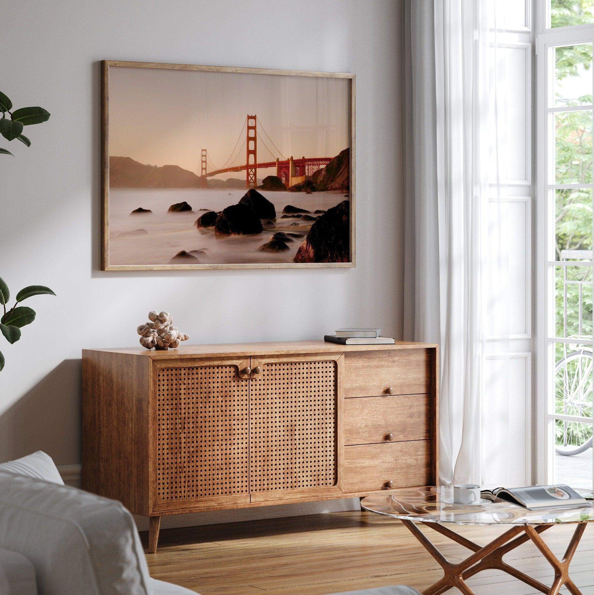 Limited-edition print: Golden Gate Bridge at sunset. Long exposure blurs ocean waves, contrasting with fiery red & orange sky. Dramatic scene with bridge framed by foreground rocks.