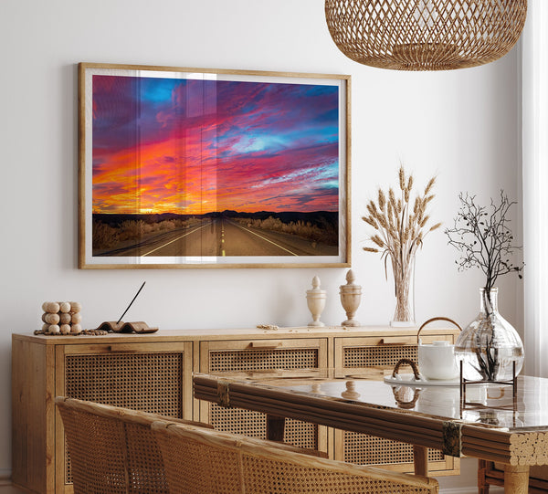 Mojave Desert Sunset Print - A captivating wall art featuring vibrant hues of a late desert sunset casting a warm glow over a timeless desert road. Perfect for desert enthusiasts and nature lovers.&quot;