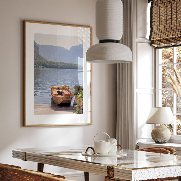 Lake house decor featuring a serene wooden boat on Lake Hallstatt, with mountains and lush greenery, perfect for tranquil spaces.