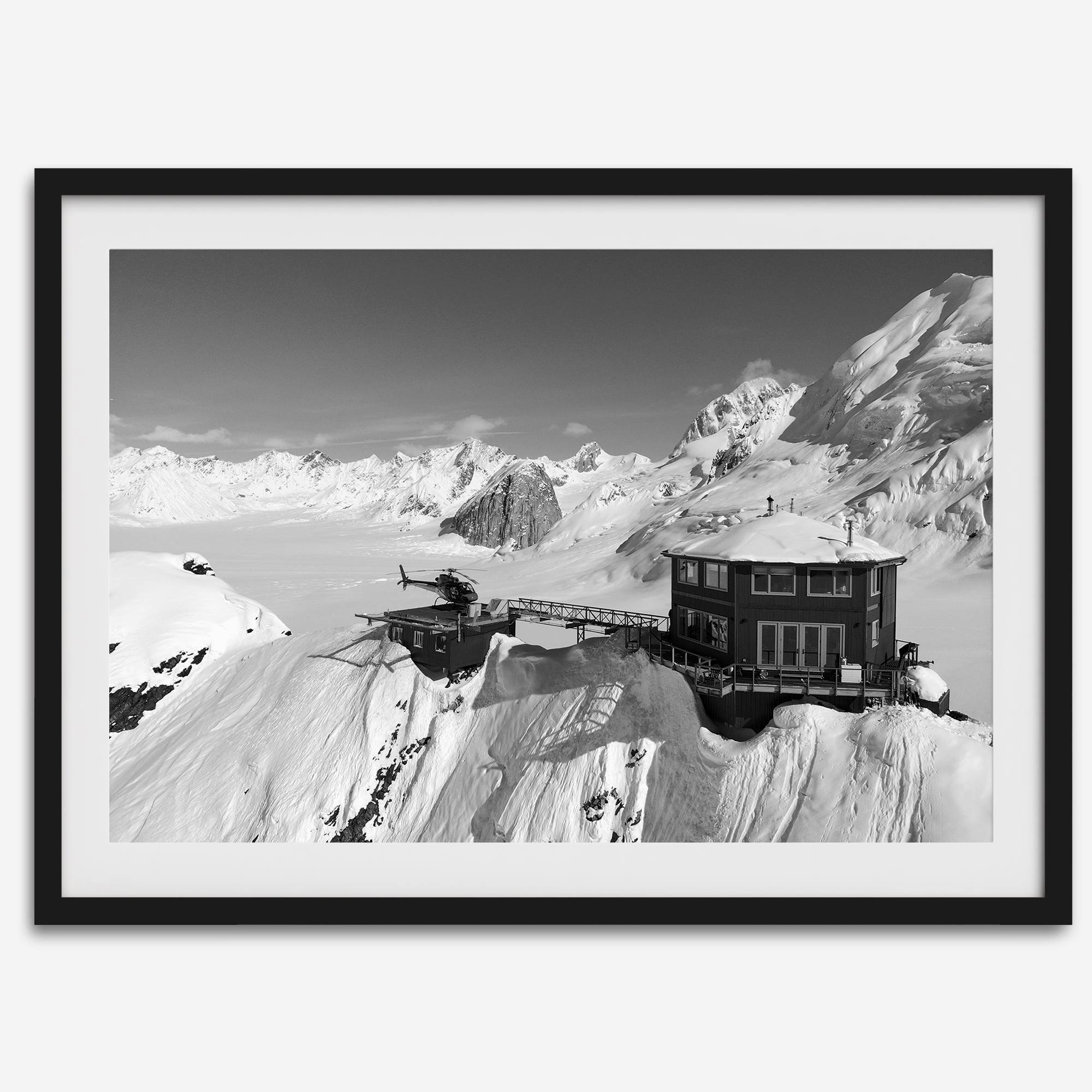 Black and white mountain cabin wall art with helicopter over snowy Denali peaks, Alaska winter landscape photography print.