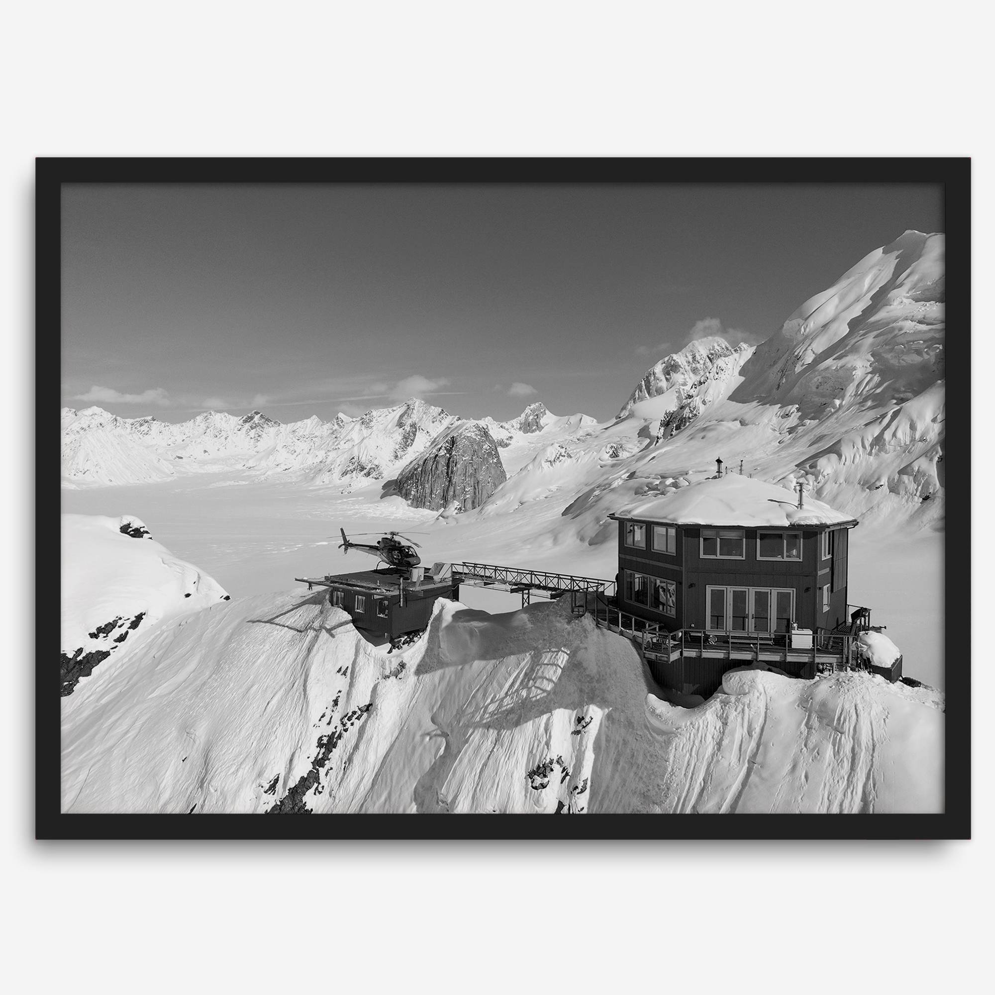 Black and white mountain cabin wall art with helicopter over snowy Denali peaks, Alaska winter landscape photography print.