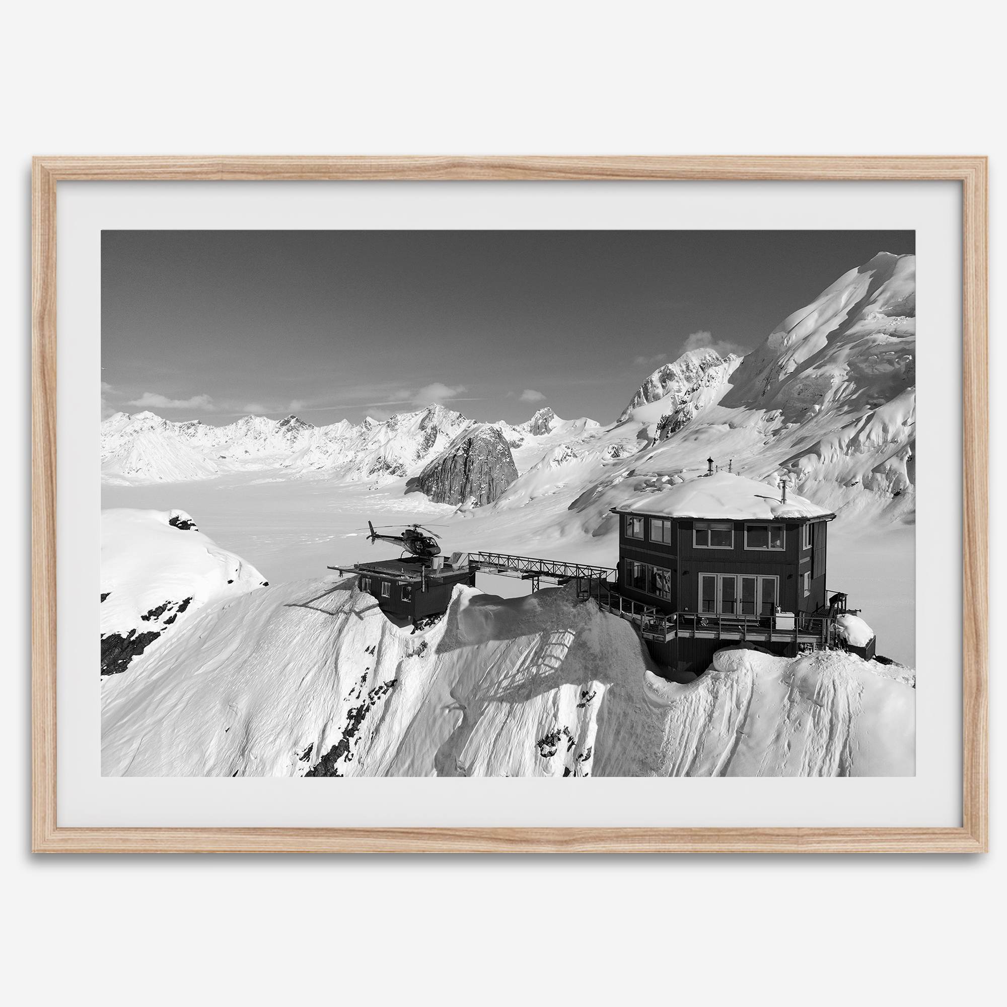 Black and white mountain cabin wall art with helicopter over snowy Denali peaks, Alaska winter landscape photography print.