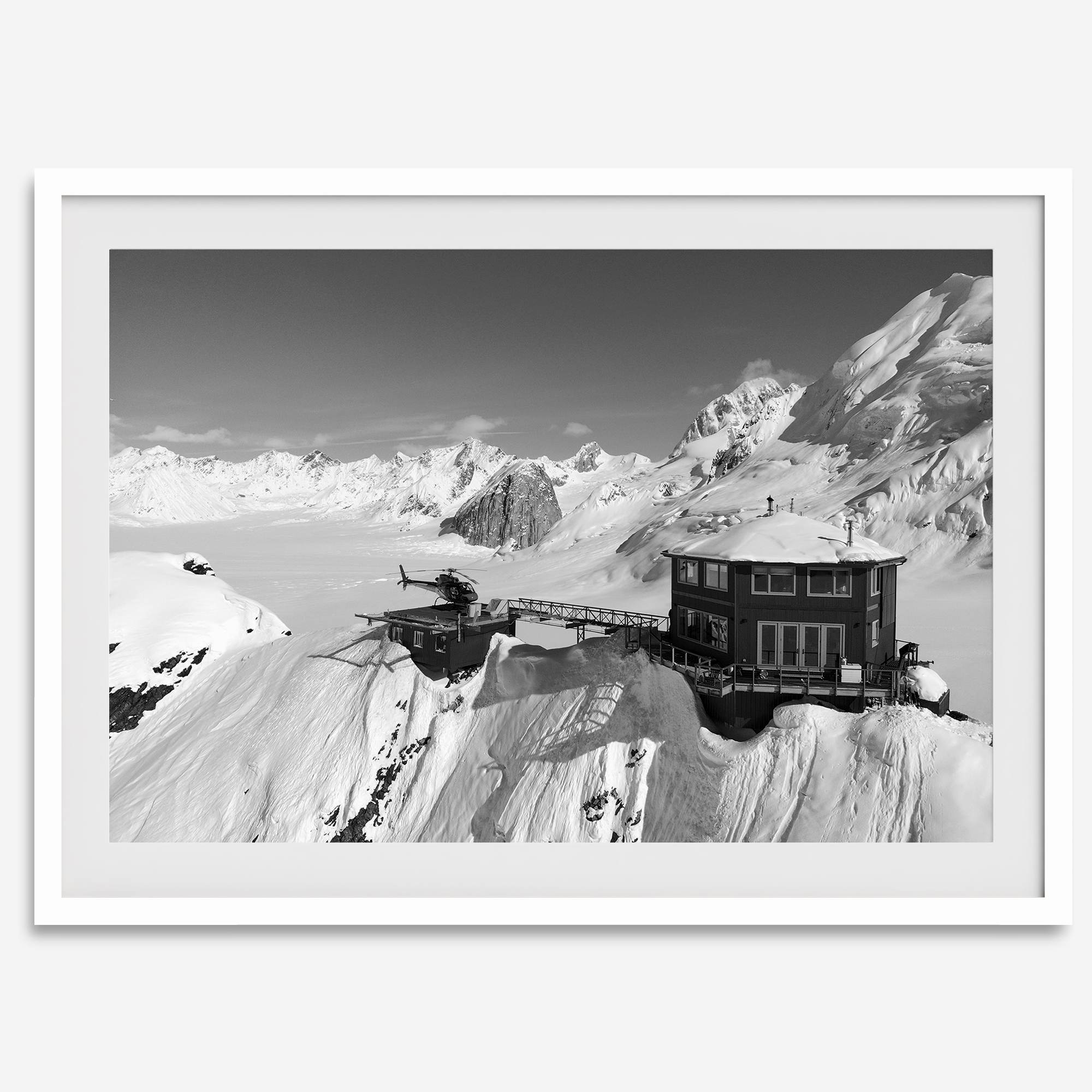 Black and white mountain cabin wall art with helicopter over snowy Denali peaks, Alaska winter landscape photography print.