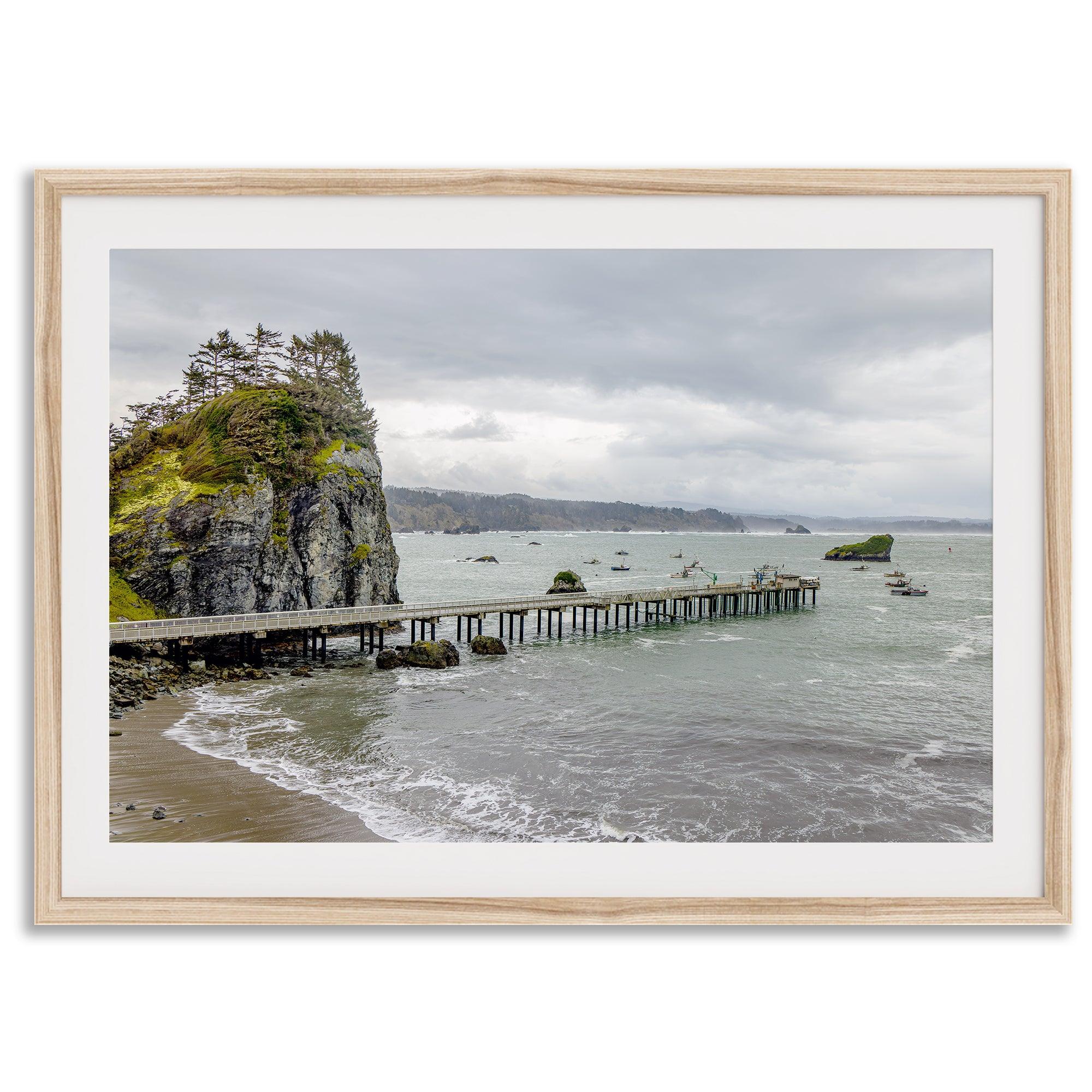 Scenic Pacific Northwest wall art of Trinidad State Park in California, showcasing a coastal pier, lush green cliffs, and calm ocean waves under cloudy skies.